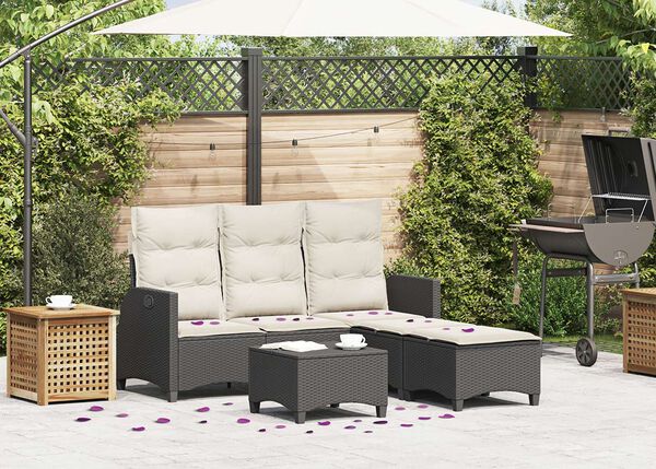 Terrassen-Lounge mit schwarzen Rattansitz-M&ouml;beln, wei&szlig;en Kissen und verstreuten violetten Bl&uuml;tenbl&auml;ttern, mit Grill und Holzaufbewahrung in der N&auml;he.