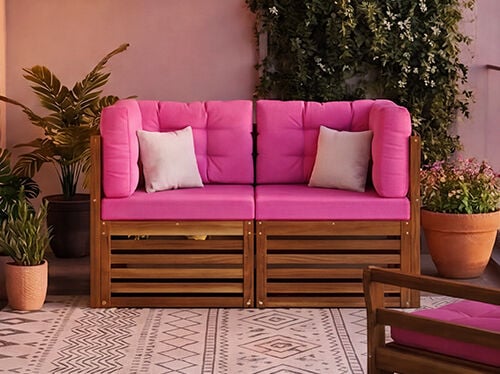 Neues modulares Balkonsofa-Set mit kr&auml;ftigen rosafarbenen Kissen und Rahmen aus Massivholz, auf einem Stadtbalkon mit Pflanzen und Glasgel&auml;nder, NEW-Badge sichtbar