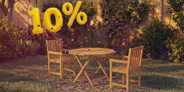 Runder Holz-Outdoor-Esstisch mit drei passenden Stühlen und Kaffeetassen in einem Gartensetting, umgeben von rosa Konfetti und goldenen 10%-Rabatt-Ballons, die ein saisonales Angebot für Outdoor-Esstische bewerben.